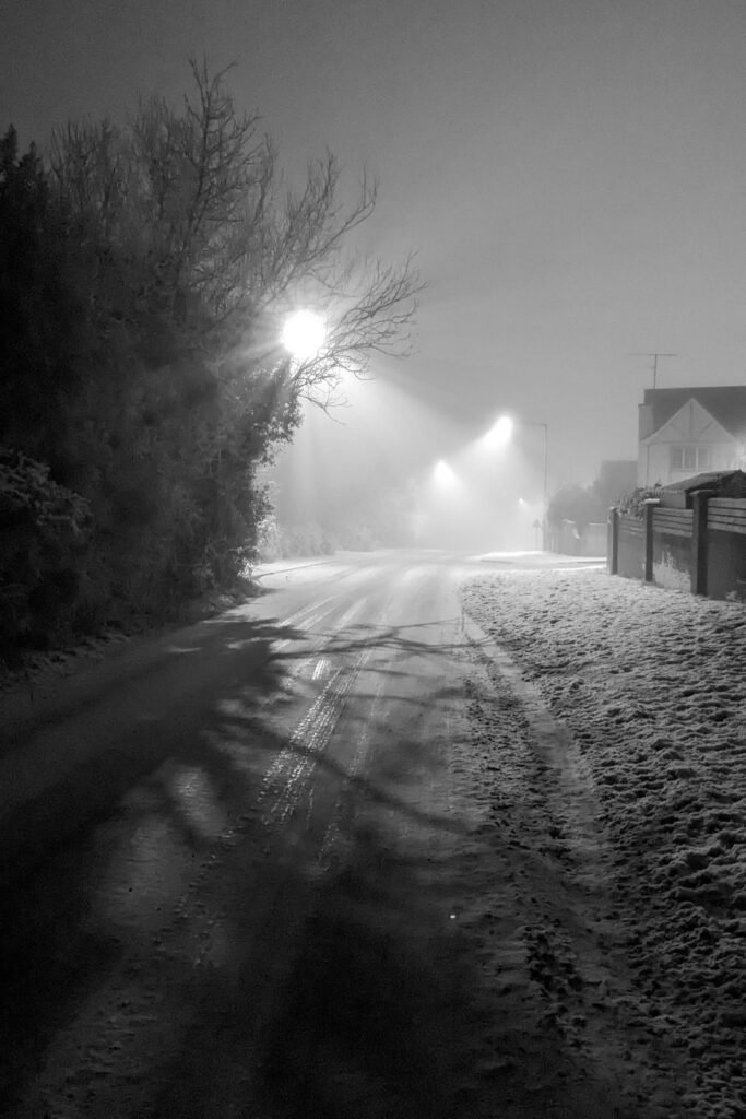 Ballinamullan road leading to Killyclogher road at night covered in snow with streetlights in fog